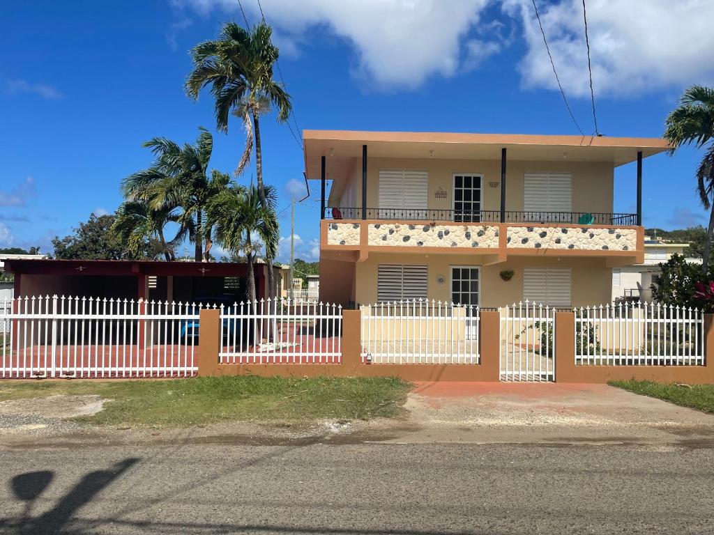una casa con una valla blanca y palmeras en Villa near Crash Boat Beach Aguadilla, PR 2nd flr en Camaceyes