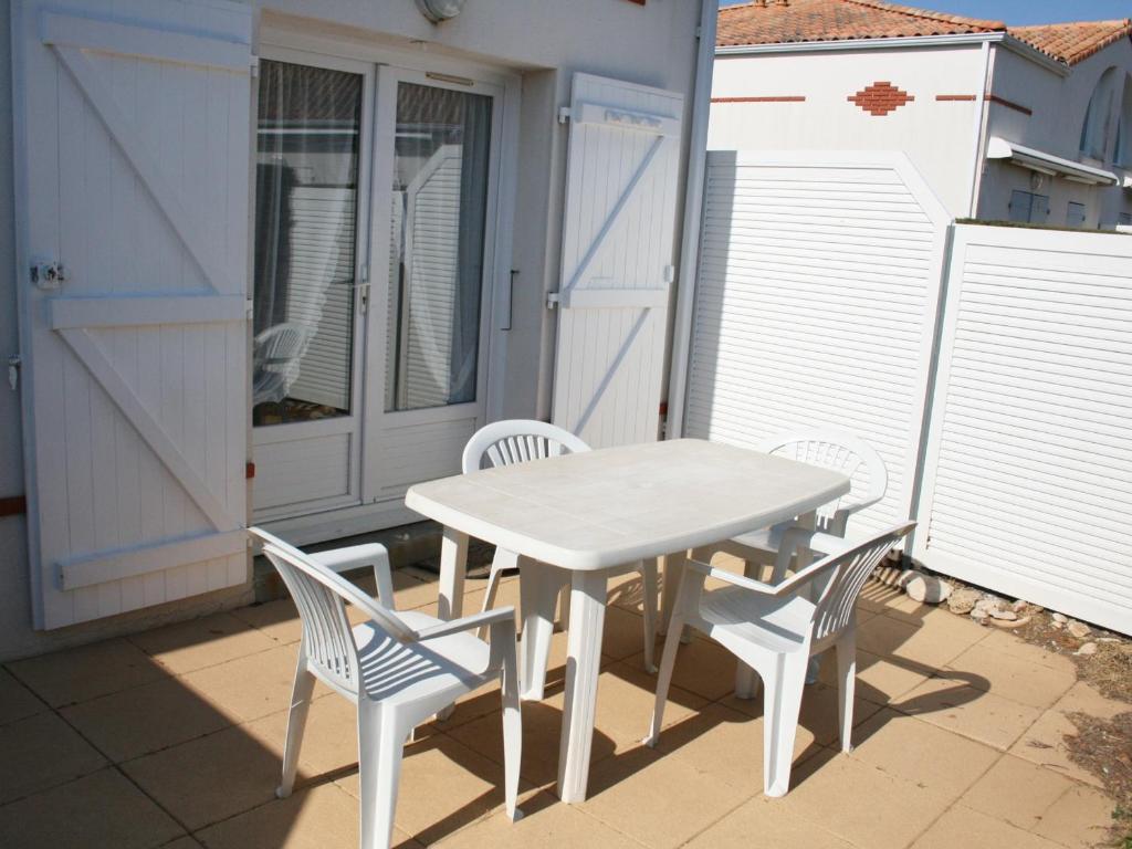 une table blanche et des chaises sur une terrasse dans l'établissement Maison à La Tranche-sur-Mer avec piscine, proche plage - FR-1-22-190, à La Tranche-sur-Mer