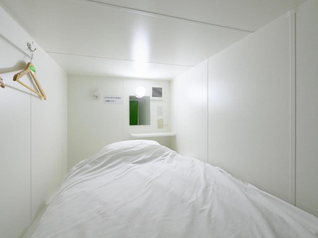 Habitación blanca con cama y espejo en Tabist カプセルイン笠懸 男性専用 Tabist Capsule Inn Kasakake Male Only, en Midori