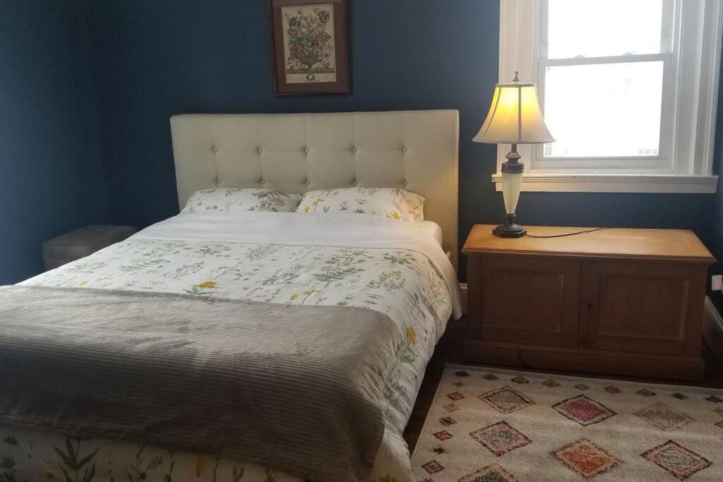 a bedroom with a bed and a lamp and a window at Charming Townhouse in Historic Town near Boston. in Dedham