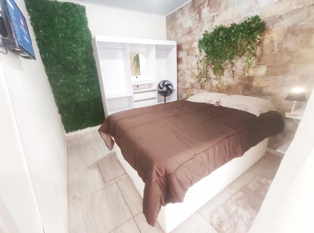 Kitnet Lua - Mobiliada في بيلو هوريزونتي: غرفة نوم بسرير كبير وجدار حجري