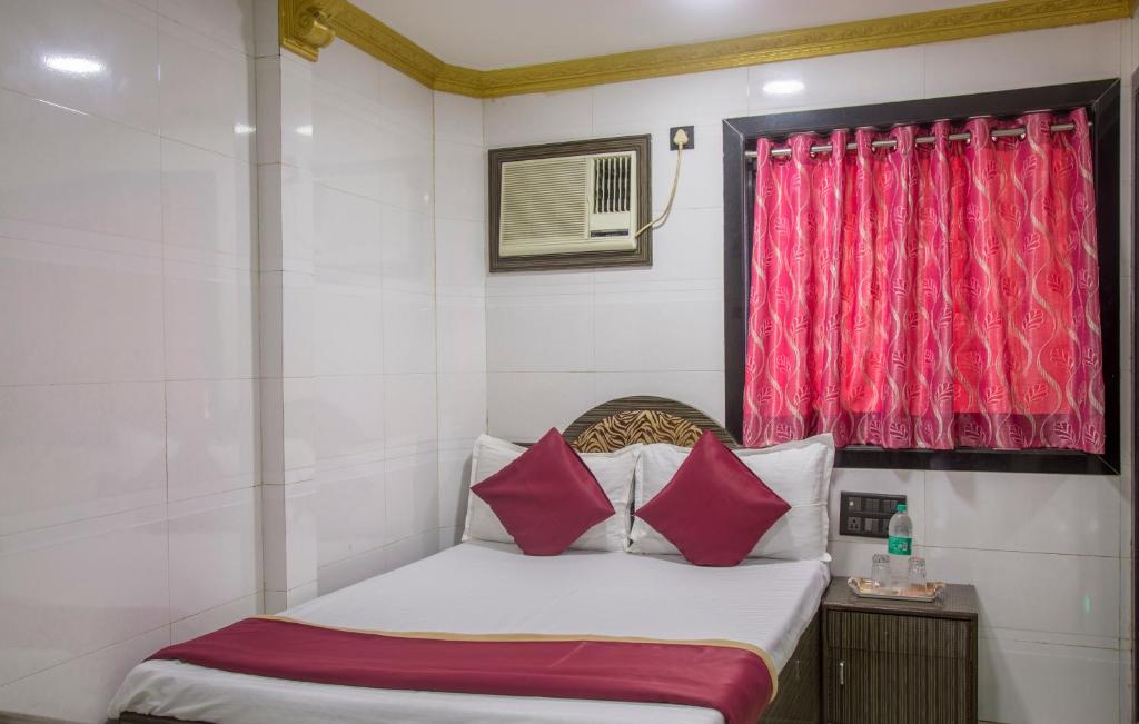 a small bedroom with a bed with red curtains at RELAX GUEST HOUSE in Mumbai