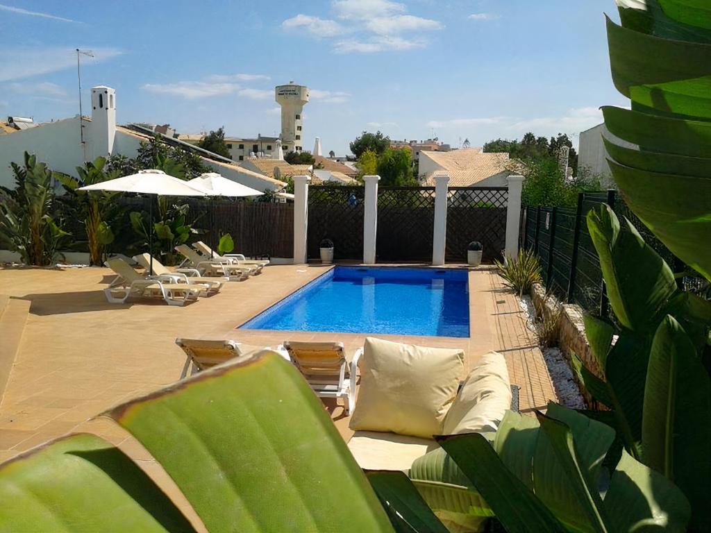 un patio con una piscina con sillas y avisor en Villa 81 amazing villa in a fantastic location on Oura Beach Albufeira, en Albufeira