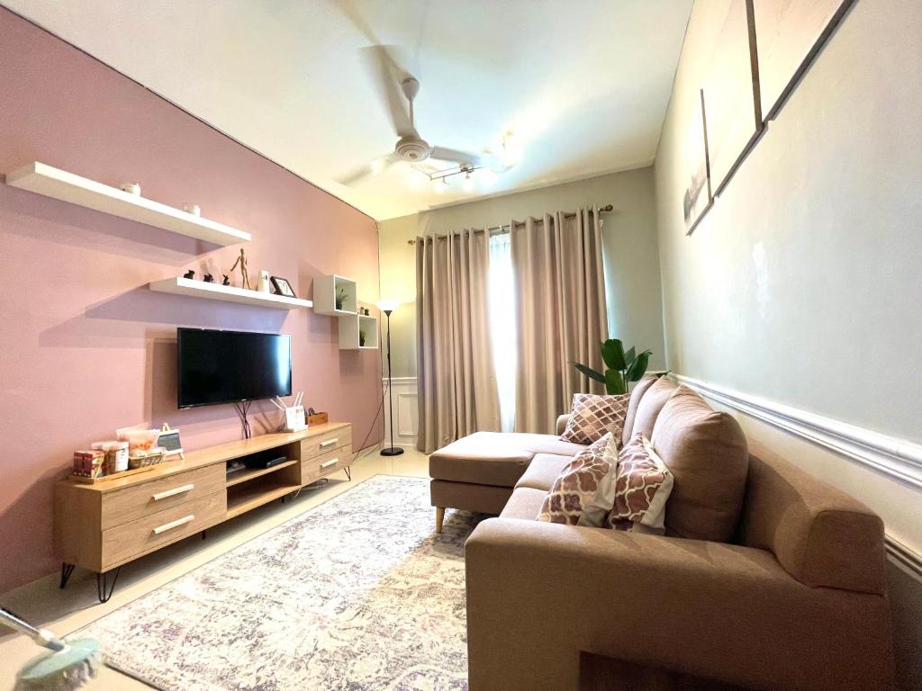 Una sala de estar con un sofá y un televisor. en Apartment in Ladang Tok Pelam, en Kuala Terengganu