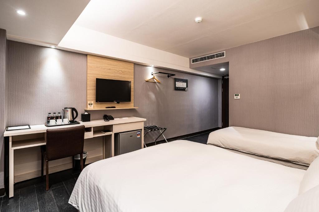 a hotel room with a bed and a desk and a tv at Global Traveler Hotel in Kaohsiung