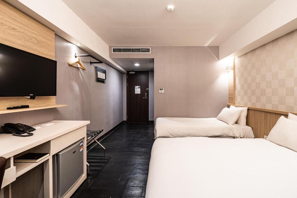 a hotel room with a bed and a tv at Global Traveler Hotel in Kaohsiung