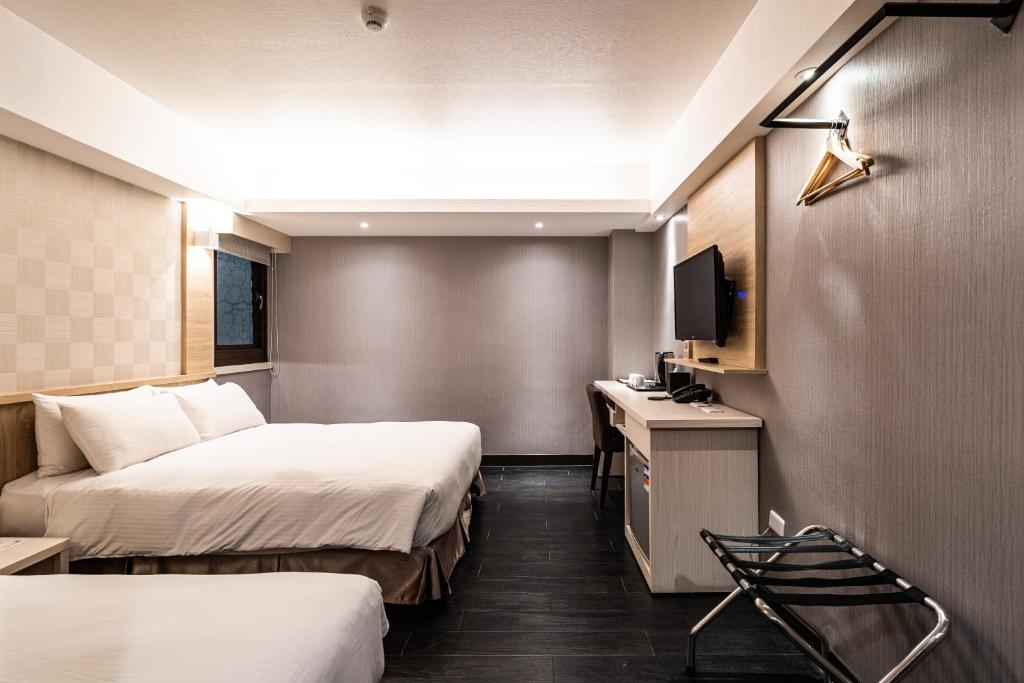 a hotel room with two beds and a television at Global Traveler Hotel in Kaohsiung