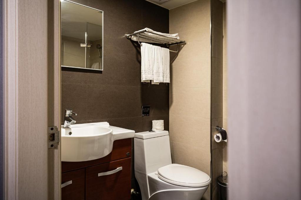 a bathroom with a toilet and a sink and a mirror at Global Traveler Hotel in Kaohsiung