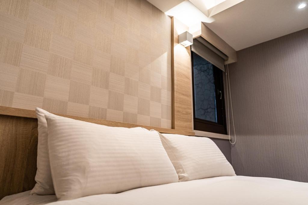 a bed with a white pillow and a window at Global Traveler Hotel in Kaohsiung