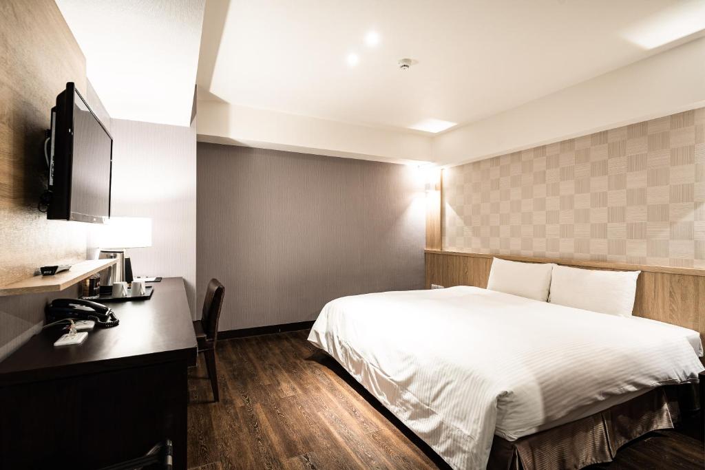 a hotel room with a bed and a desk at Global Traveler Hotel in Kaohsiung