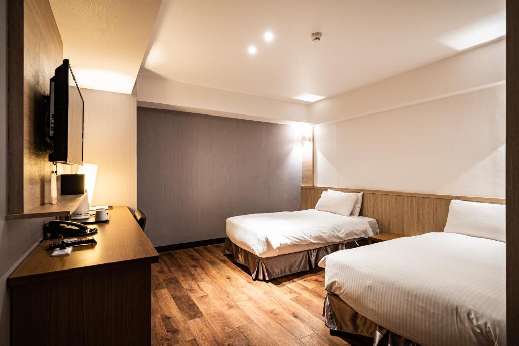 a hotel room with two beds and a desk at Global Traveler Hotel in Kaohsiung