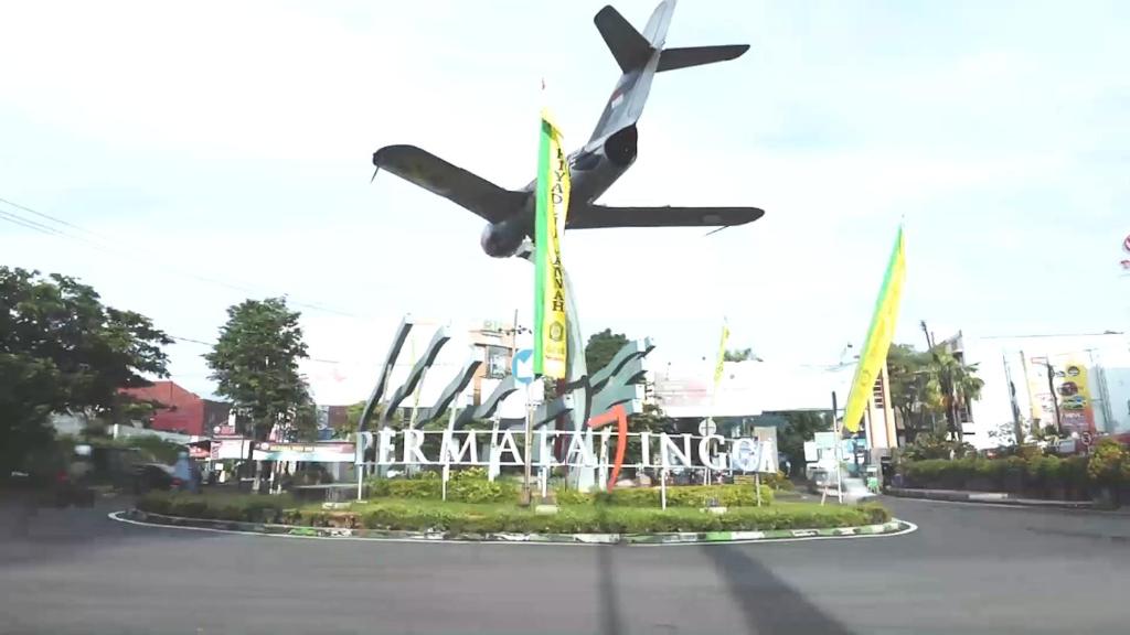 Um avião está a sobrevoar uma placa numa rua em Villa Samawa em Malang