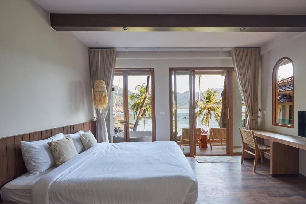a bedroom with a bed and a desk with a view of the ocean at Resolution Resort in Ko Chang