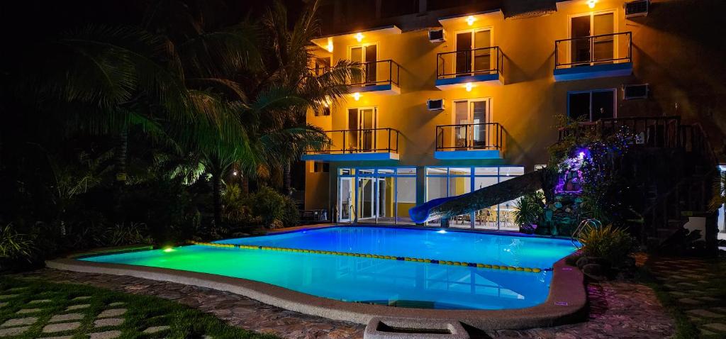 a swimming pool in front of a building at night at Crystal Shores Beach Resort powered by Cocotel in Malawin