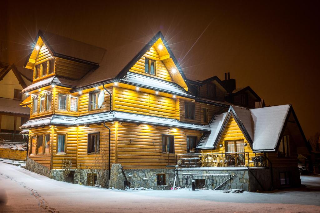 a large wooden house with snow on it at Dom Wypoczynkowy Dolinka in Białka Tatrzańska