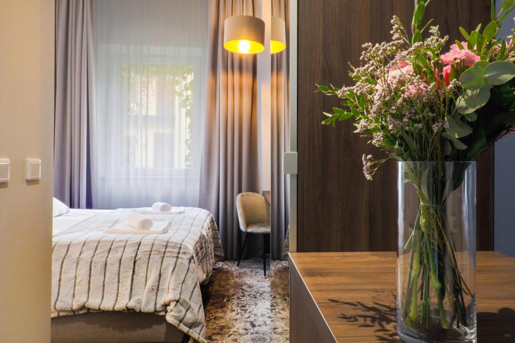 a bedroom with a bed and a vase of flowers on a table at Aparthotel Cracovia Residence in Krakow