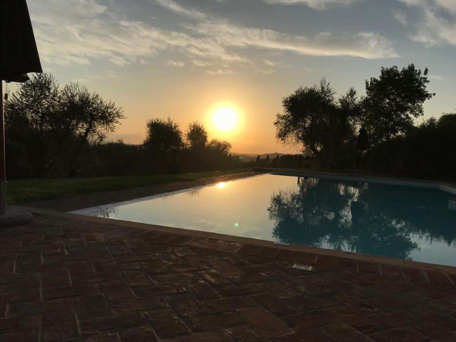 una piscina con puesta de sol en el fondo en Rododendro casa sulle colline Toscane vicino San Giminiano en Castelfalfi