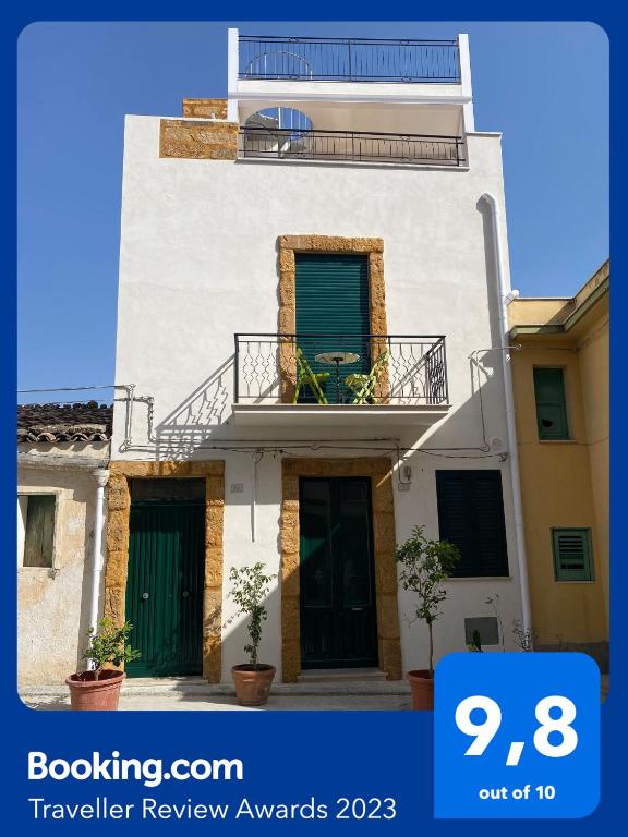 a white house with green doors and a balcony at Vista Baglio Grande in Sambuca di Sicilia