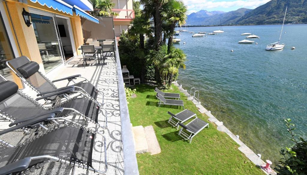 balkon z krzesłami i łodziami w wodzie w obiekcie Villa Genovese al Lago w mieście Minusio