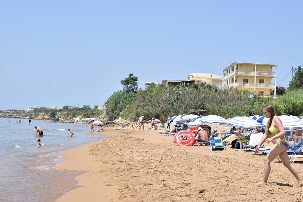 a group of people on a beach with umbrellas at SUNSET BAY STUDIOS in Agios Georgios