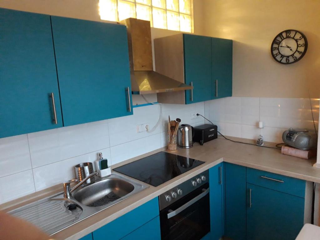 a kitchen with blue cabinets and a sink and a clock at Apartmán Sejkorka Vrchlabí in Vrchlabí
