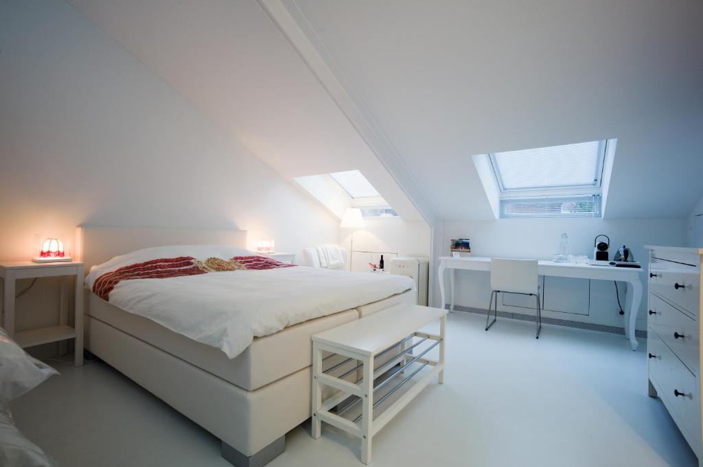 - une chambre blanche avec un lit et un lavabo dans l'établissement B&B De Kloostertuin, à Middelbourg