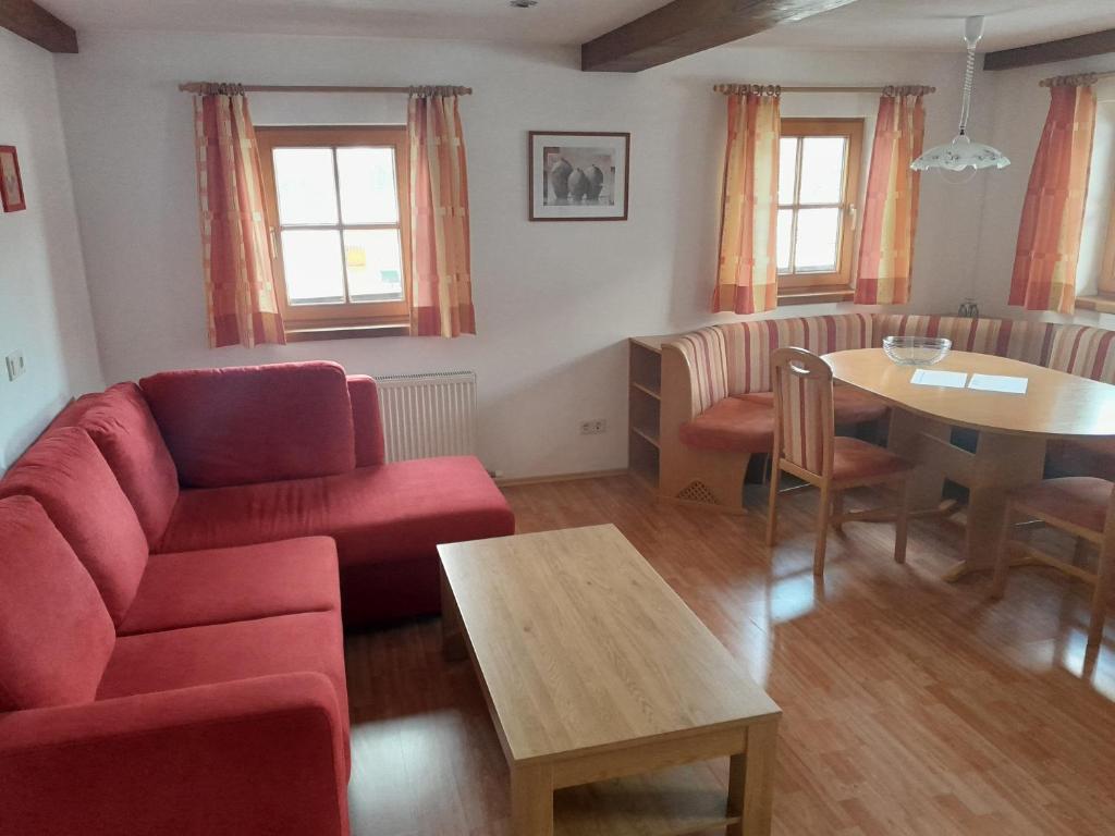 uma sala de estar com um sofá vermelho e uma mesa em BIO Bauernhof GEISL em Sankt Ulrich am Pillersee