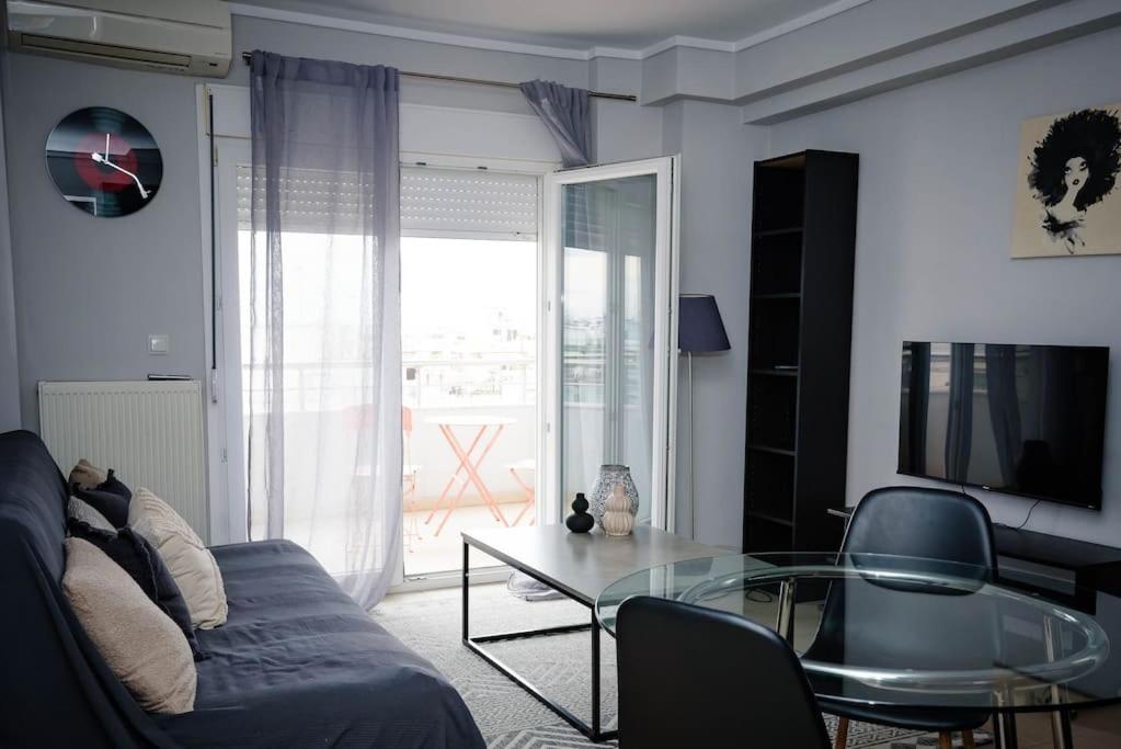 un soggiorno con divano blu e tavolo in vetro di Stelina’s Cosy Loft - Ideal Spot a Salonicco
