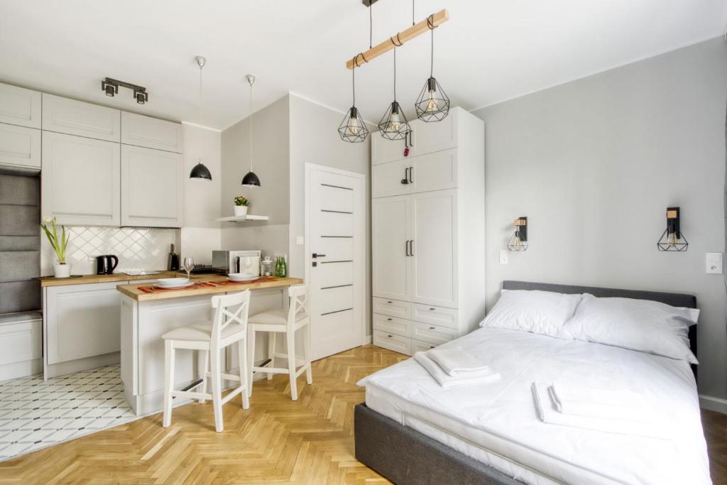 Biała sypialnia z łóżkiem i kuchnią w obiekcie KING APART Dickensa w Warszawie