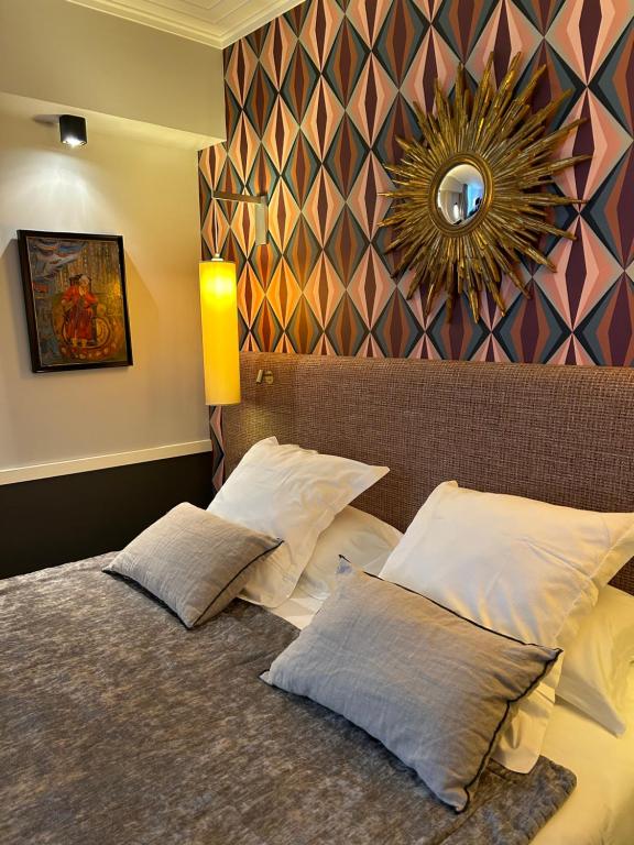 a bedroom with a bed with two pillows and a mirror at Hôtel jardin Le Pasteur in Châlons-en-Champagne