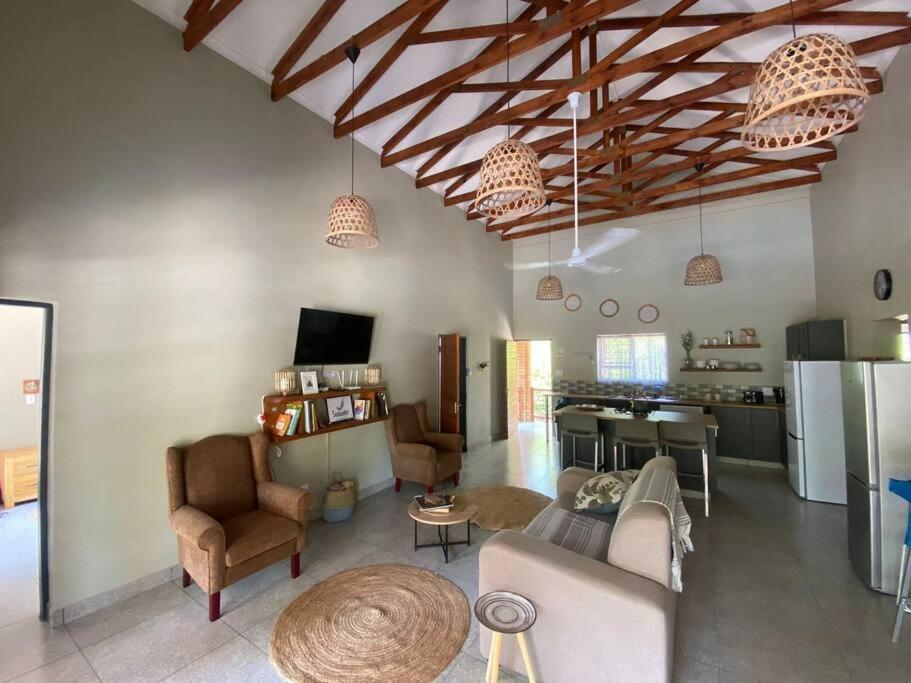 a living room with couches and chairs and a kitchen at Sonador Bush House in Marloth Park