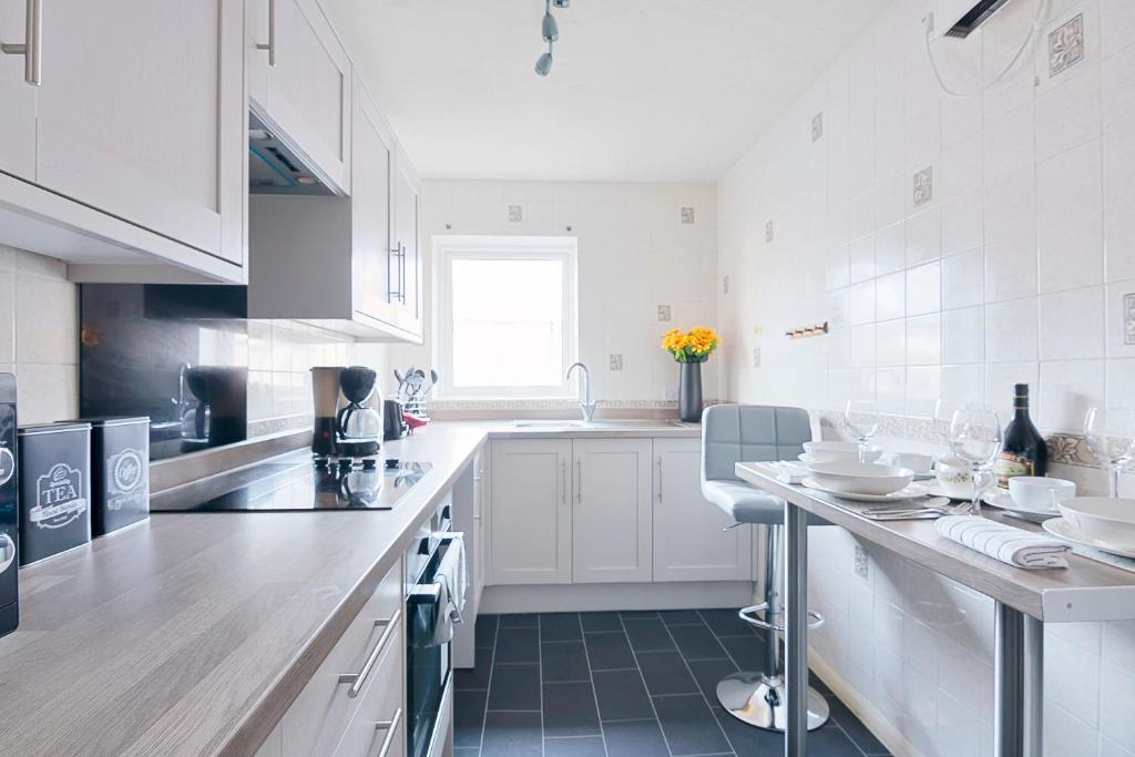 eine weiße Küche mit weißen Schränken und einer Theke in der Unterkunft Elegance Graceland in Gillingham