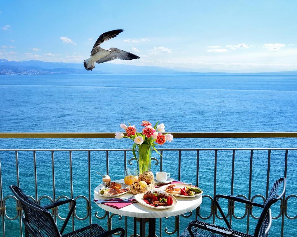 une table avec de la nourriture et un oiseau survolant l'eau dans l'établissement Hotel Savoy, à Opatija