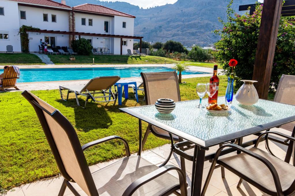 a table with a bottle of wine and two glasses at Posidonia Luxury Villas Kolympia in Kolimbia