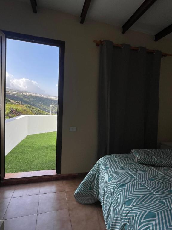 Un dormitorio con una cama y una gran puerta corrediza de vidrio. en Sunset Dream, casa en la playa con terraza, en La Laguna