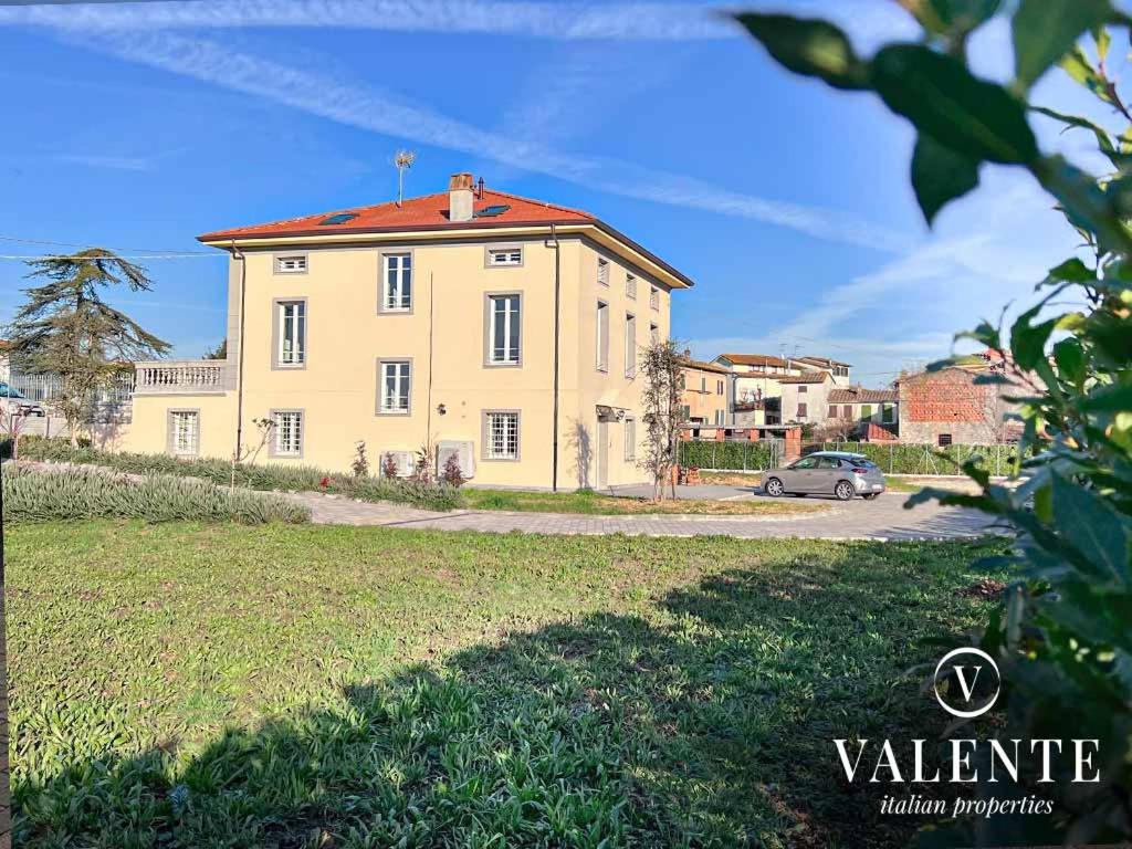 una grande casa gialla con una macchina parcheggiata di fronte di Villa Valente - Apartments a Capannori