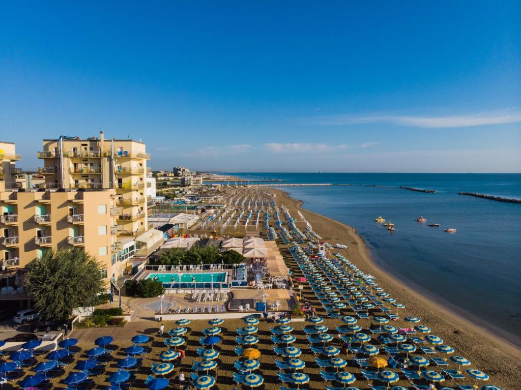 une plage avec beaucoup de parasols et de voitures garées dans l'établissement Bikini Tropicana Family Hotel, à Lido di Savio