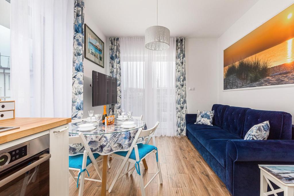 a living room with a blue couch and a table at Apartament Holiday 8/25 in Rewal