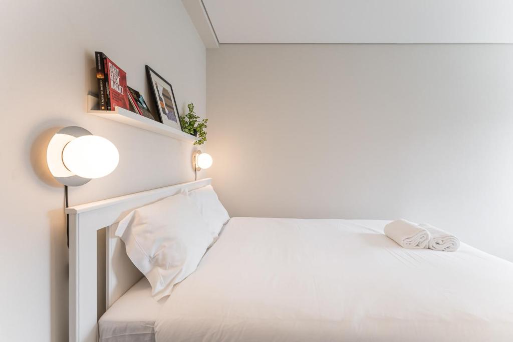 - une chambre blanche avec un lit et une lampe dans l'établissement GuestReady - Amazing stay near Cedofeita Church, à Porto