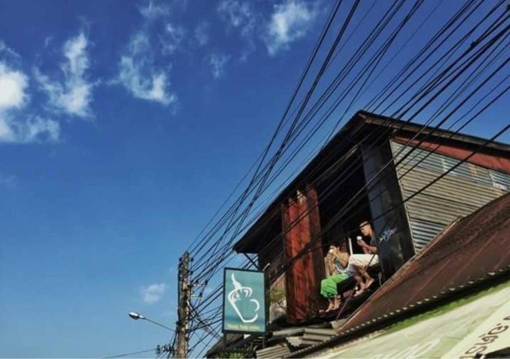 une personne assise sur une fenêtre d'un bâtiment avec un chien dans l'établissement ทุ่งยั้งเฮ้าส์, à Uttaradit