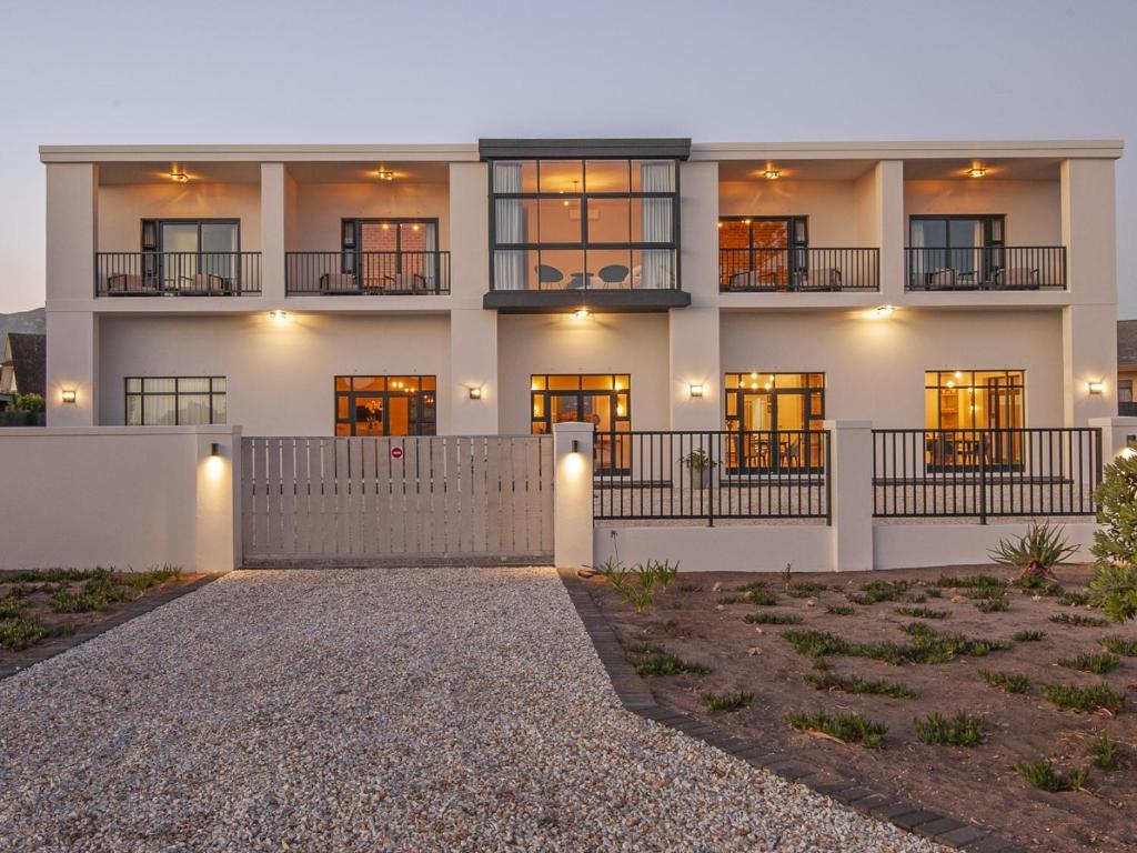 a large white building with windows and a driveway at Glow Boutique Suites in Hermanus
