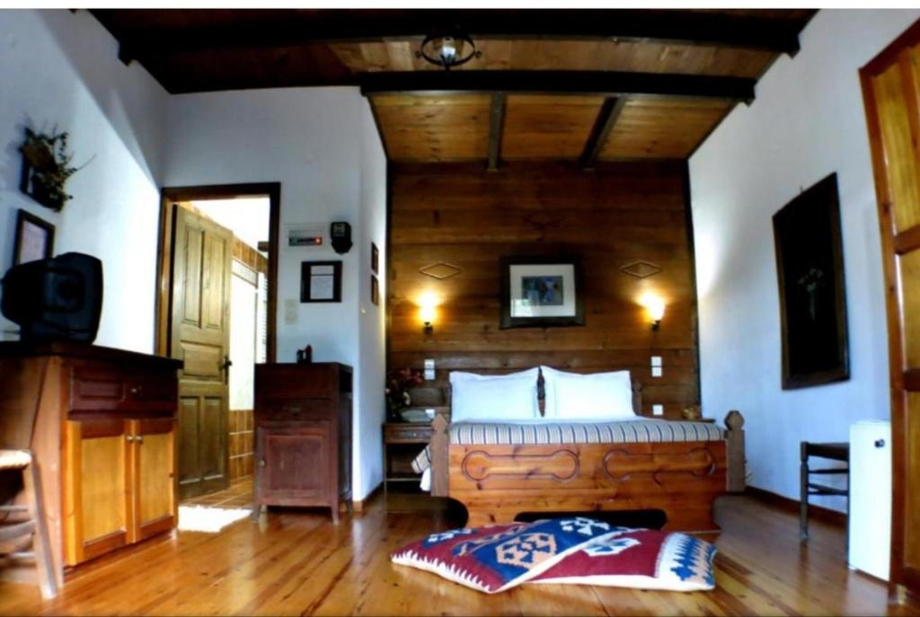 sypialnia z dużym łóżkiem i drewnianym sufitem w obiekcie Xenonas Brizi w mieście Elati Trikalon