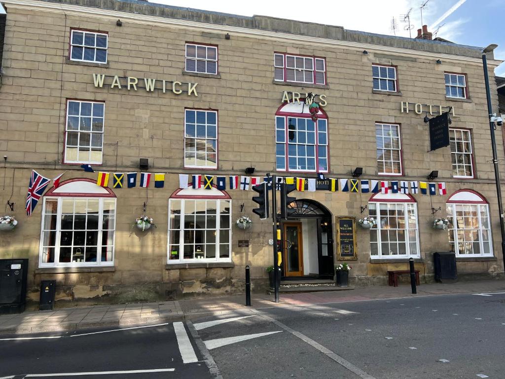 un edificio con banderas en la parte delantera en The Warwick Arms Hotel en Warwick