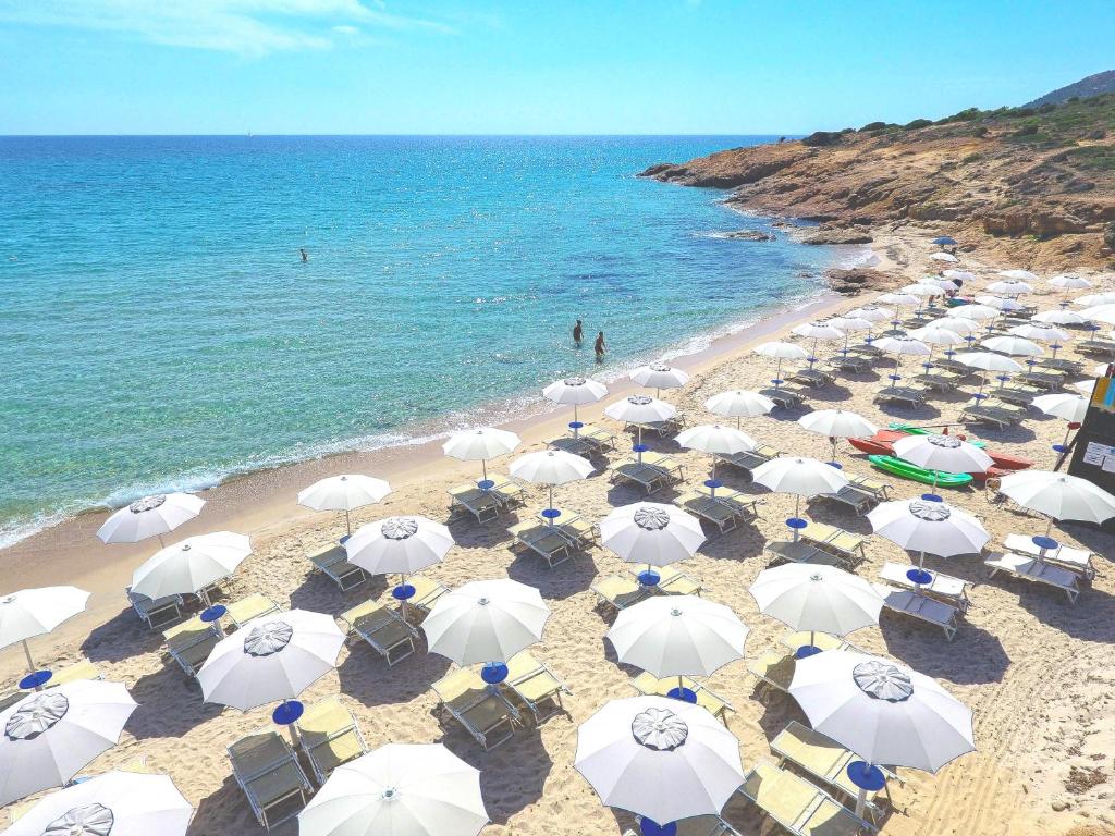 an overhead view of a beach with white umbrellas at Amareclub Rocca Dorada in Santa Margherita di Pula