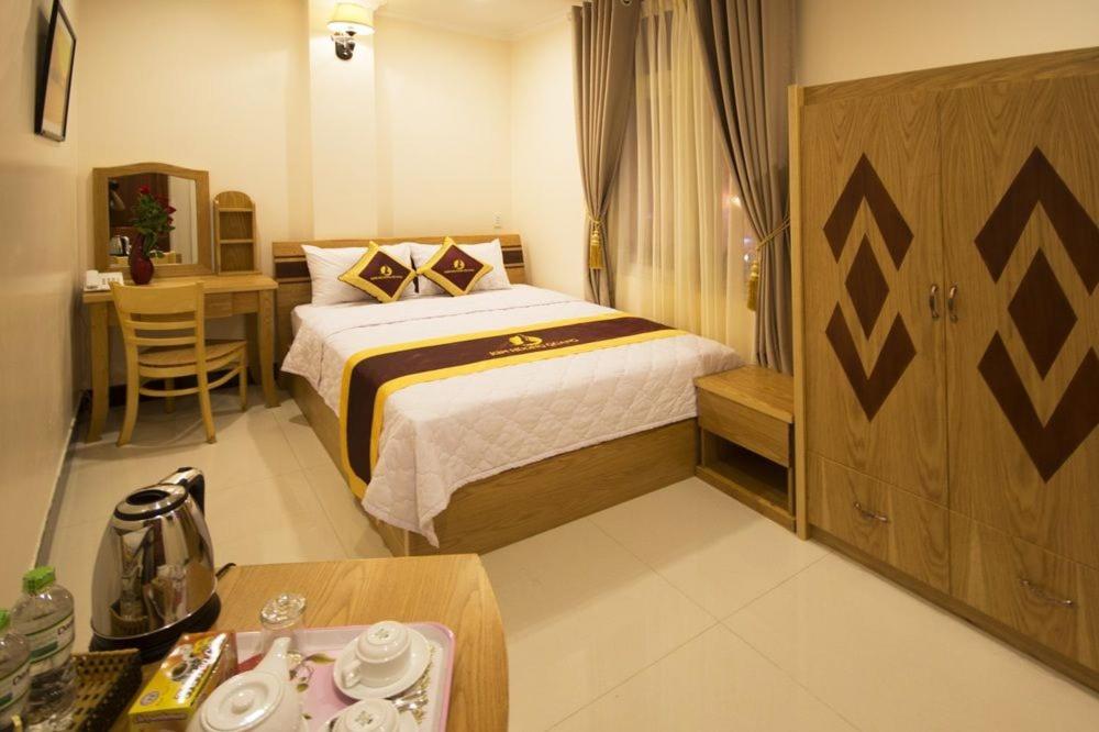 ein Hotelzimmer mit einem Bett, einem Schreibtisch und einem Tisch in der Unterkunft Kim Huong Quang Hotel in Phu Quoc