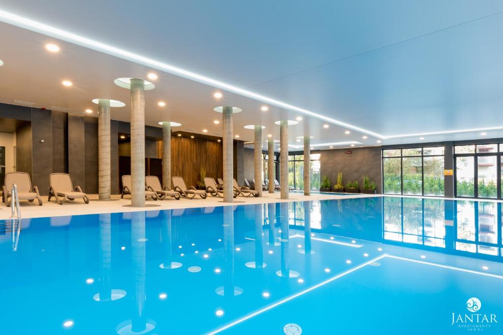 a swimming pool in a hotel with chairs at Jantar Apartamenty - Boutique Polanki Park SPA in Kołobrzeg