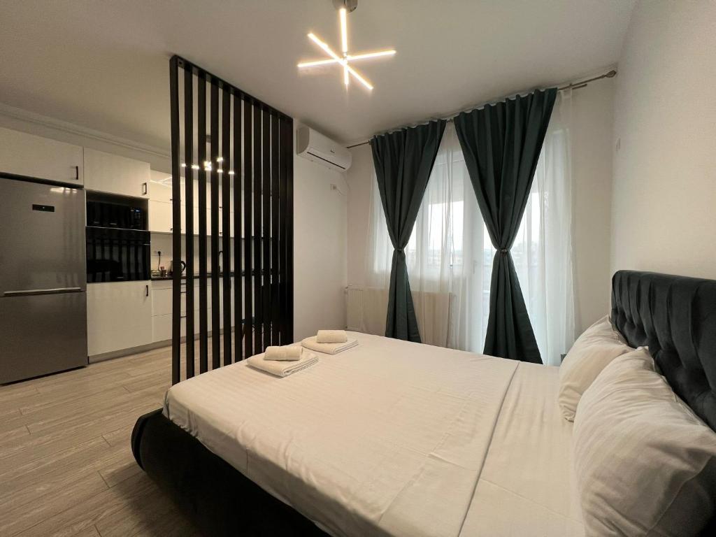 a bedroom with a large white bed and a kitchen at Perfect Host Palas in Iaşi