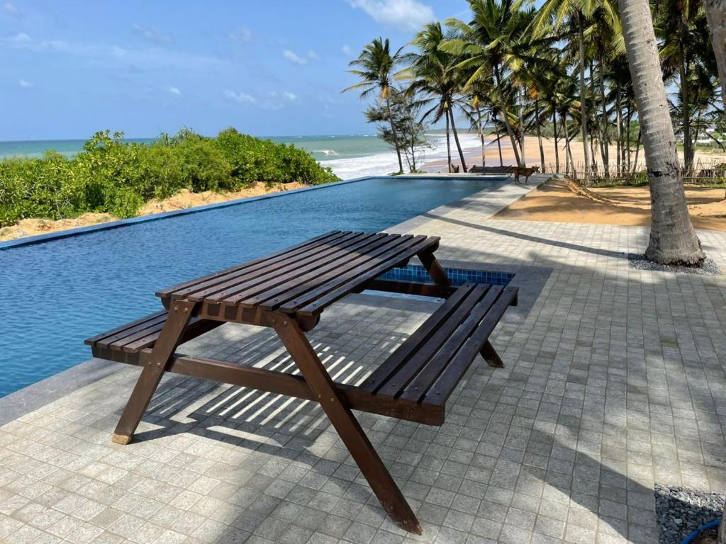a wooden bench sitting next to a swimming pool at Ocean Cottage in Kalametiya