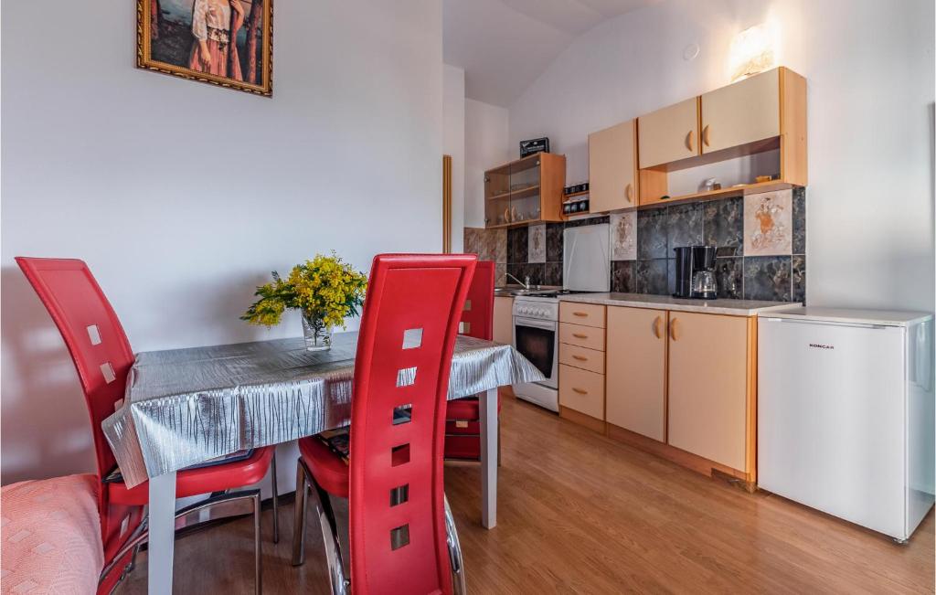 a kitchen and dining room with a table and red chairs at 1 Bedroom Cozy Apartment In Liznjan in Ližnjan