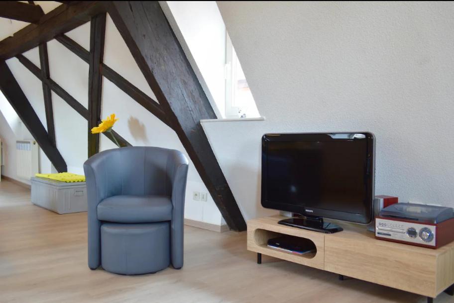 a living room with a blue chair and a tv at Bretzel &amp; Raisin - Hypercentre de Colmar in Colmar